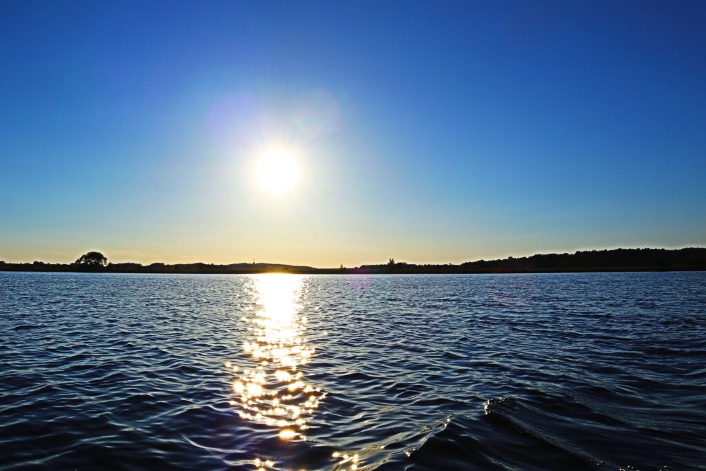 Der Große Zernsee bei Werder (Havel). Hinter dem Ufer geht die Sonne unter
