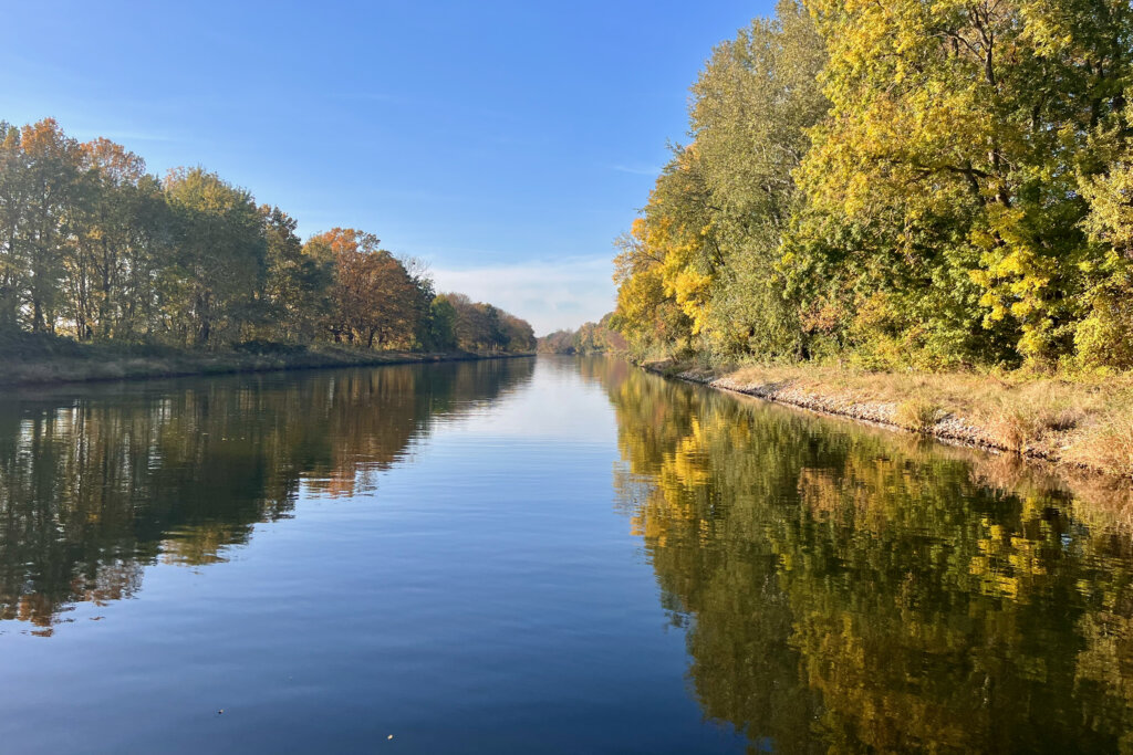 Der Sacrow-Paretz-Kanal in Brandenburg wird von herbstlichen Bäumen gesäumt, die sich im Wasser spiegeln.