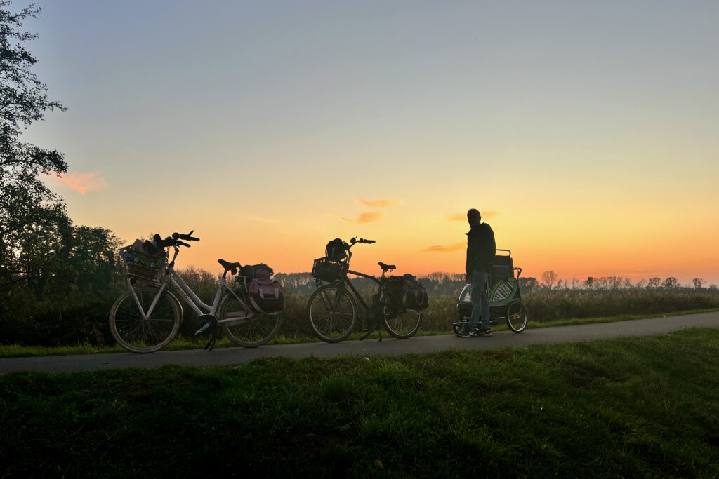 Zwei Fahrräder und eine Person bei Sonnenuntergang.